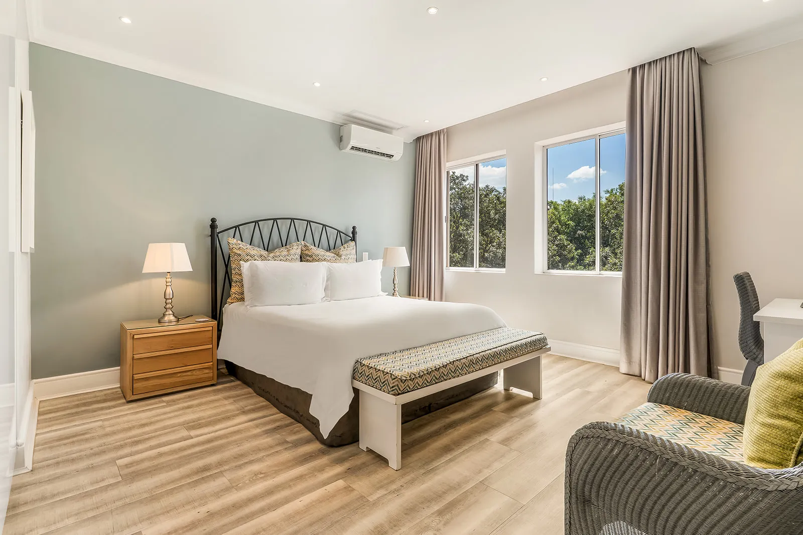 Master bedroom with sage-green feature wall, plush king bed and wide garden-view windows | Studio Stay on Sixty6 boutique hotel & accommodation in Sandton